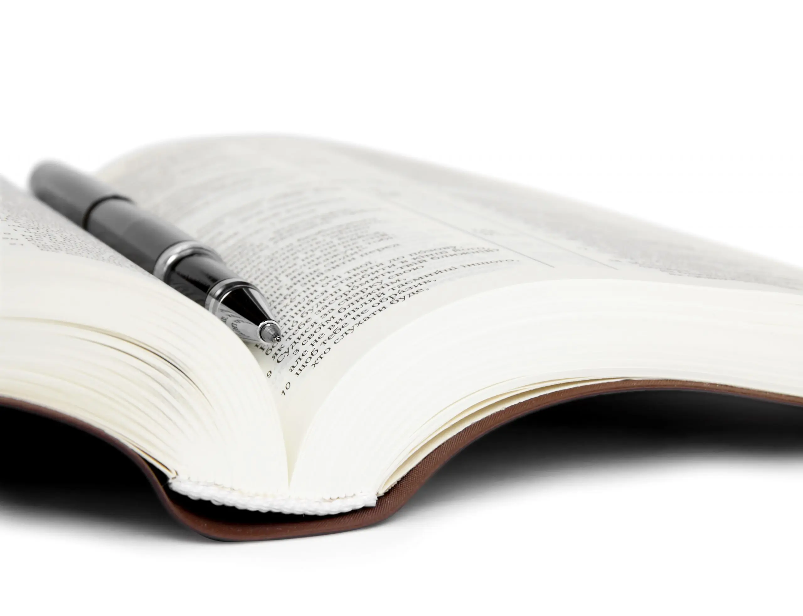 Open book with text, a black pen resting in the center.