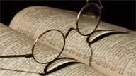 Round glasses on an open book with visible text.
