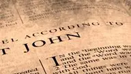 Close-up of an open Bible, showing the beginning of the Gospel of John.