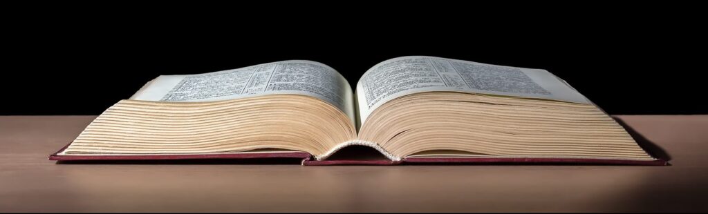 Open book on a wooden table against a black background.
