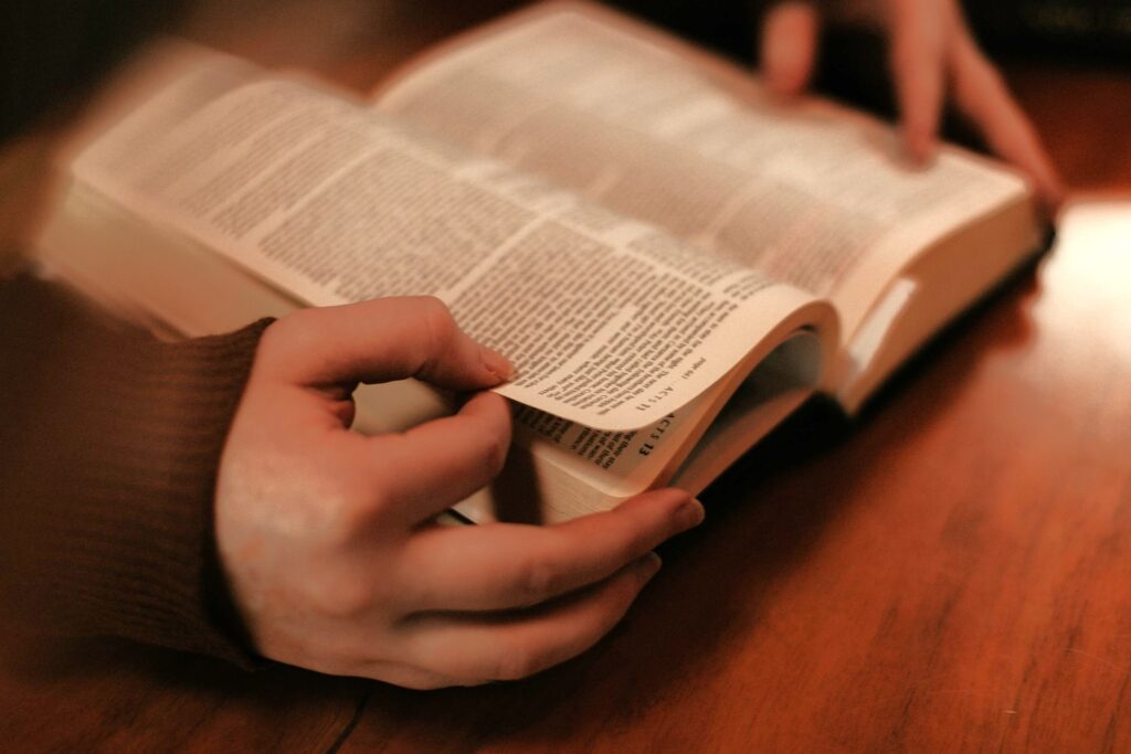 Hands flipping through a book on a wooden table.